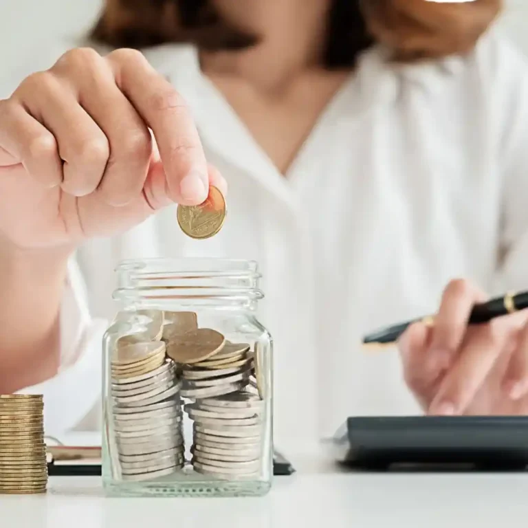 Persona guardando monedas en un frasco de ahorro